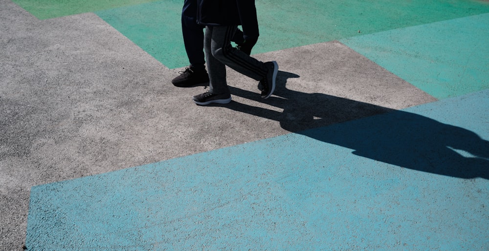 uomo in pantaloni neri e scarpe di pelle nera in piedi sul pavimento di cemento grigio