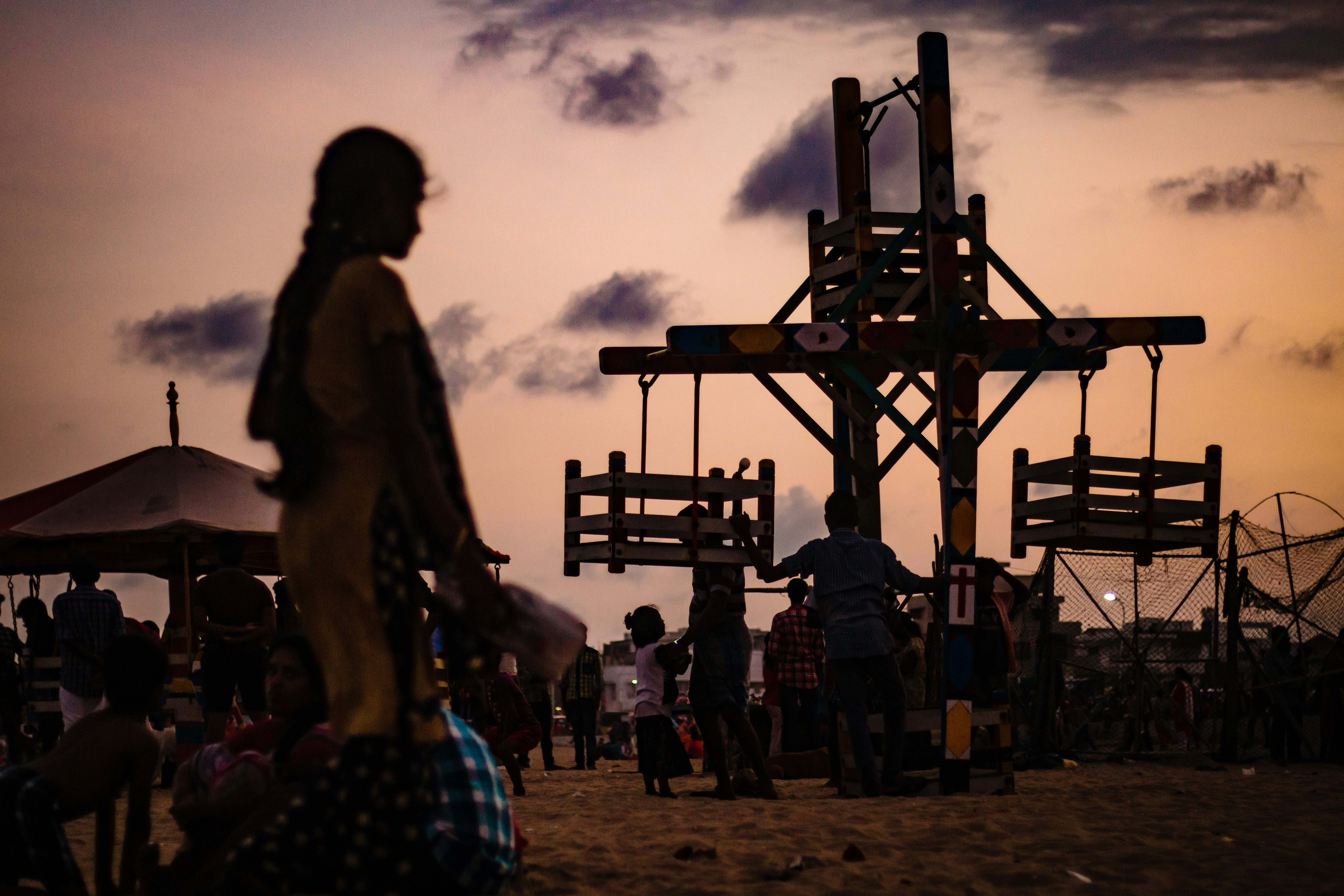 Silhouetted figures at a carnival during sunset