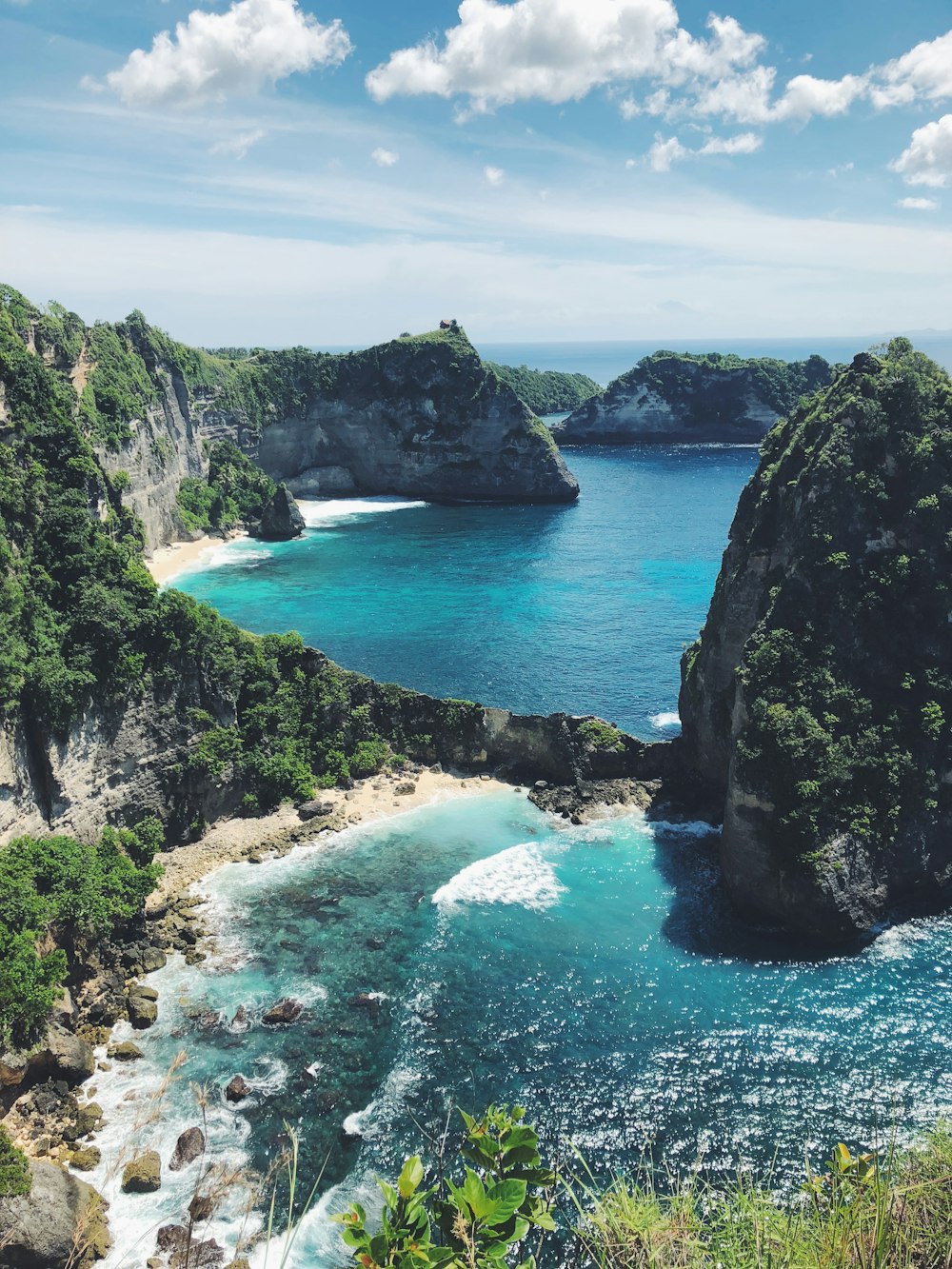 Montaña rocosa verde y marrón junto al mar azul bajo el cielo azul durante el día