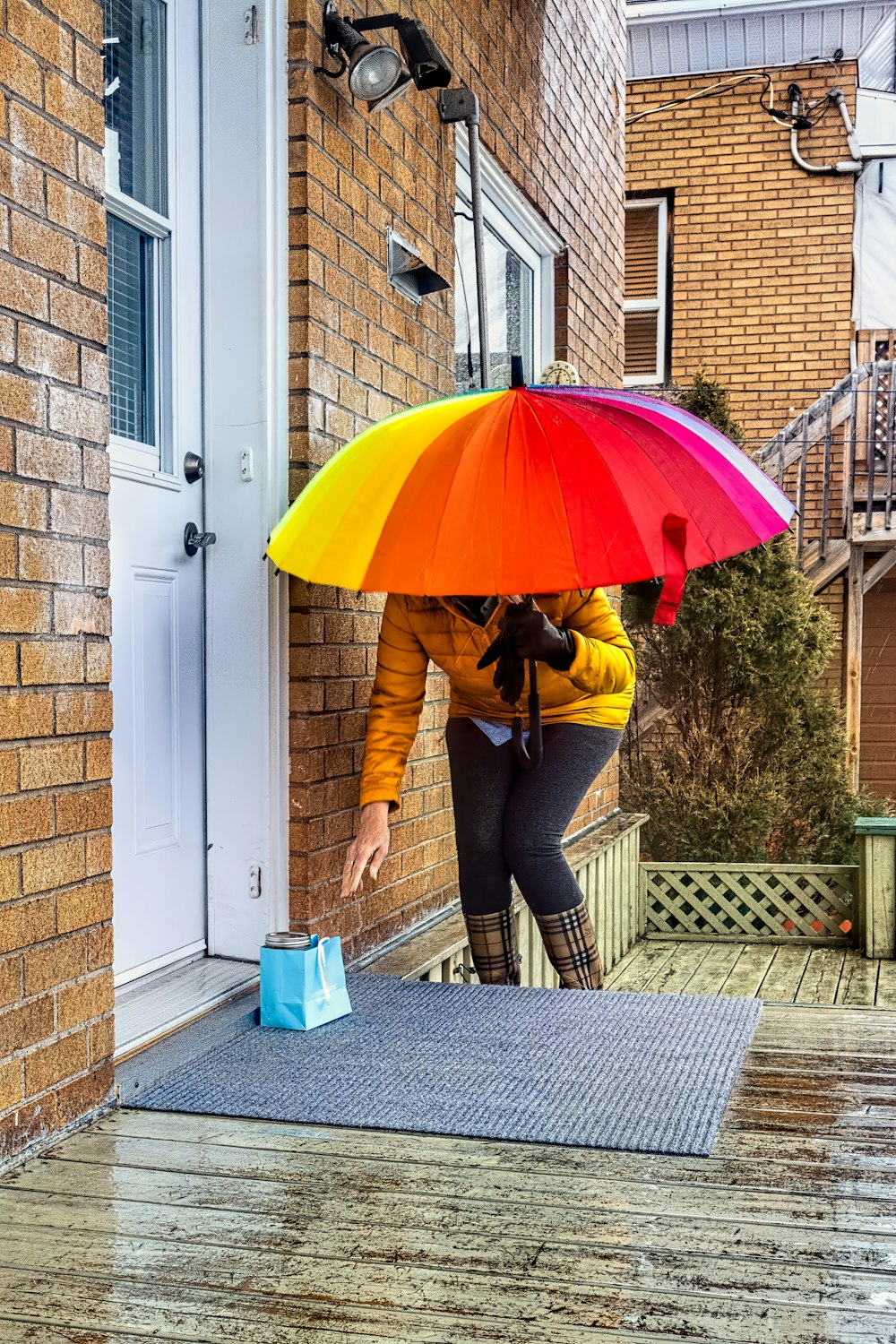 갈색 재킷과 파란색 데님 청바지에 빨간 우산을 들고 있는 여자
