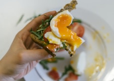 person holding cooked food with white cream on white ceramic plate