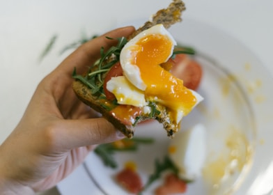 person holding cooked food with white cream on white ceramic plate