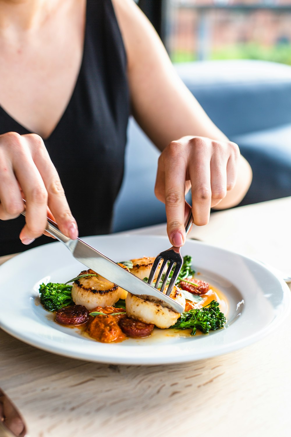 person holding fork and steak on plate