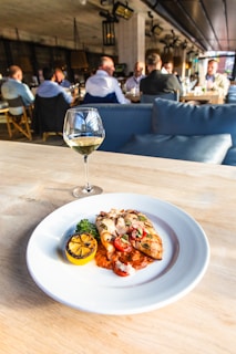 A vibrant plate of spicy grilled chicken with fresh herbs and lemon wedges on a rustic wooden table.