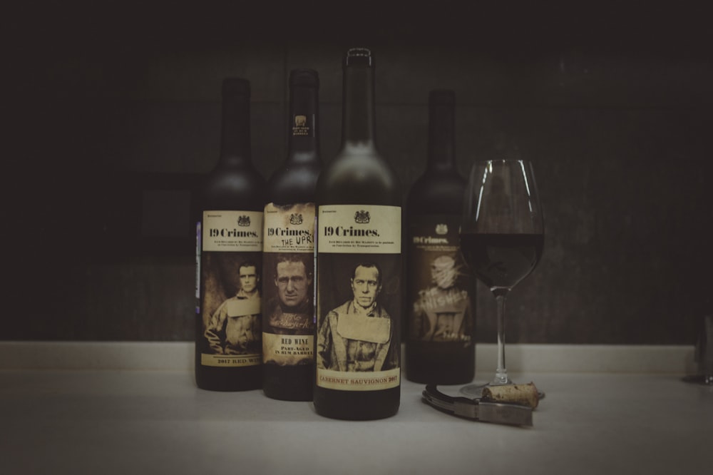 três garrafas de vinho ao lado de um copo de vinho