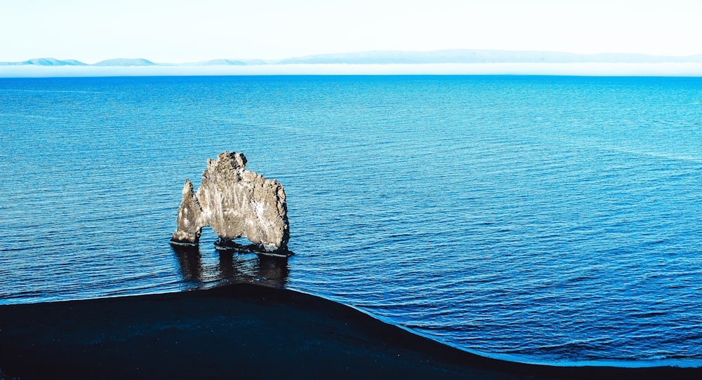 Formación de rocas grises en agua de mar azul durante el día