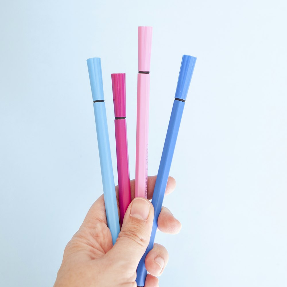 person holding blue and pink pen