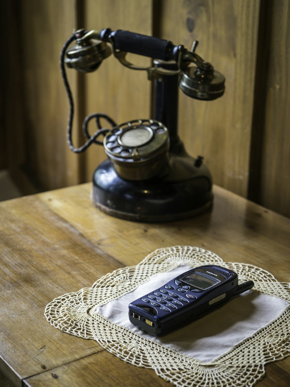 telefono fisso nero e argento su tappetino da tavolo lavorato a maglia bianco