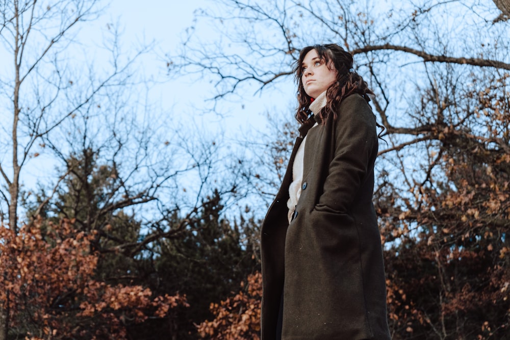 woman in black coat standing near bare tree during daytime