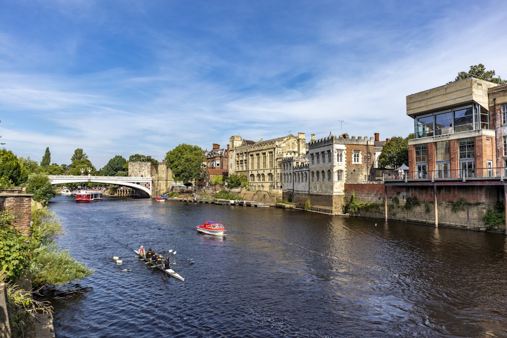 people riding on boat on river near buildings during daytime