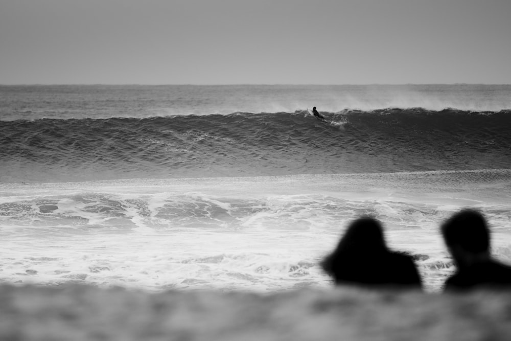 grayscale photo of woman sitting on beach