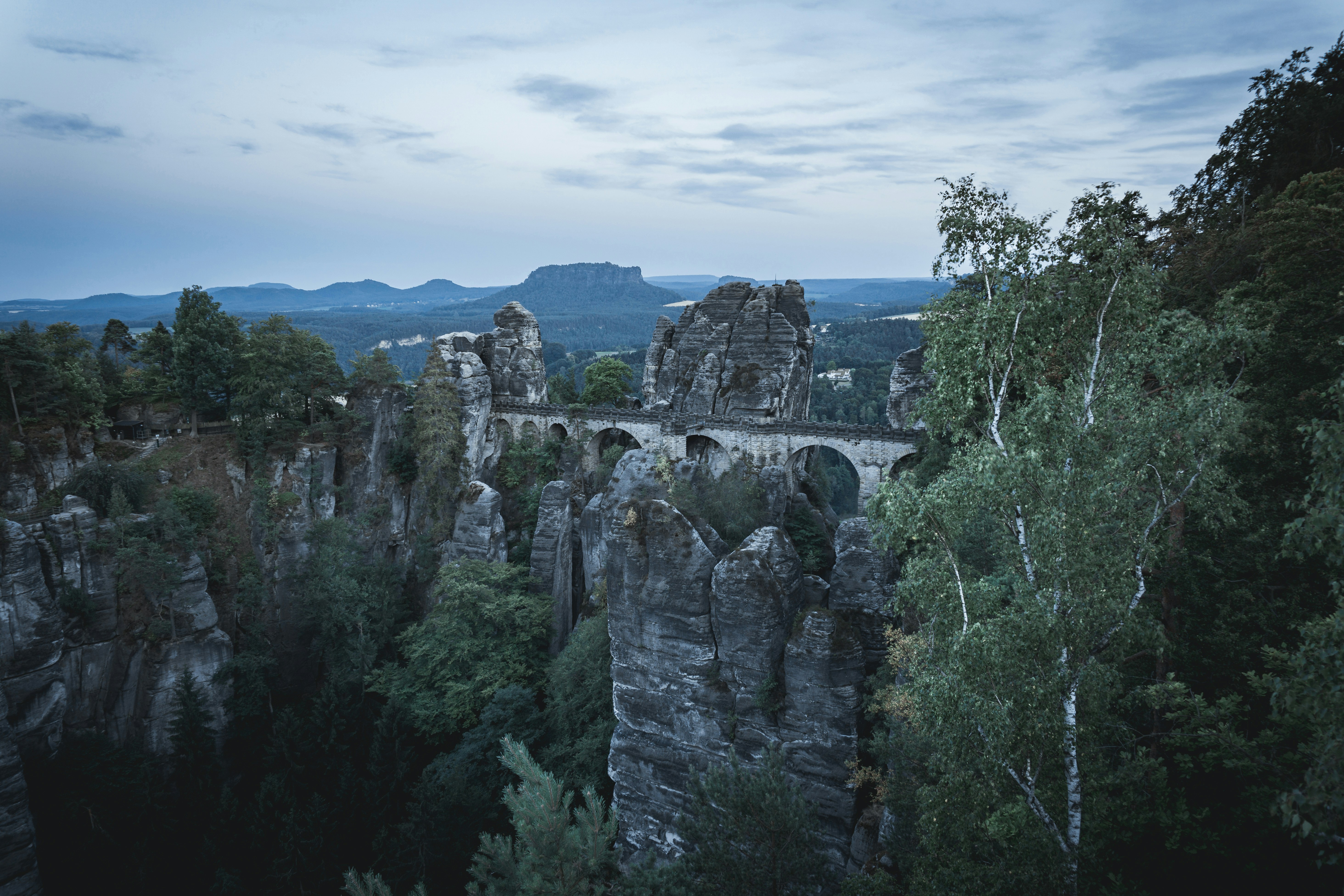 green trees on rocky mountain under white cloudy sky during daytime