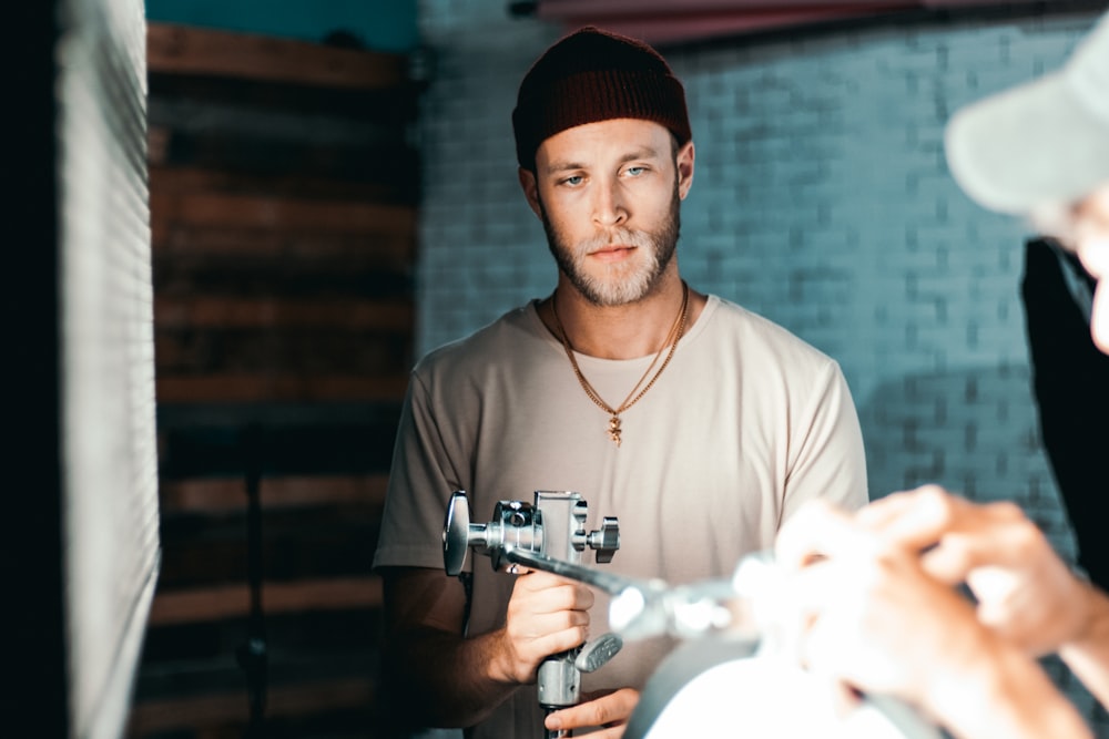 man in brown crew neck shirt holding gray and silver video camera