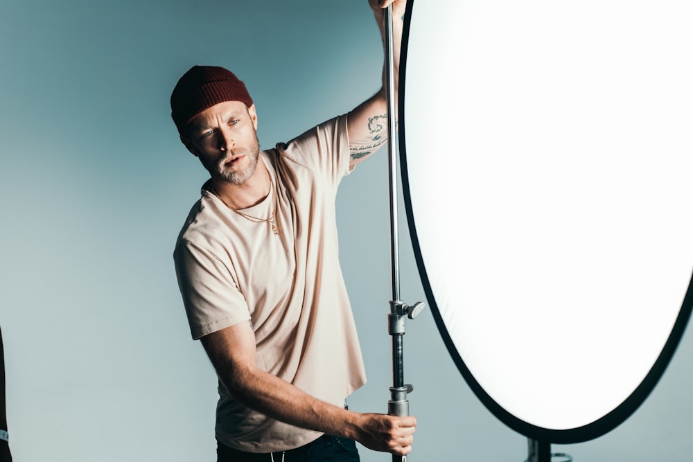 man in brown crew neck t-shirt wearing red knit cap holding microphone