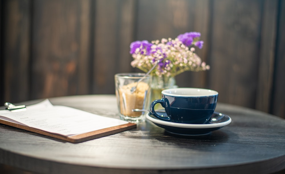 blue ceramic cup on saucer beside purple flowers