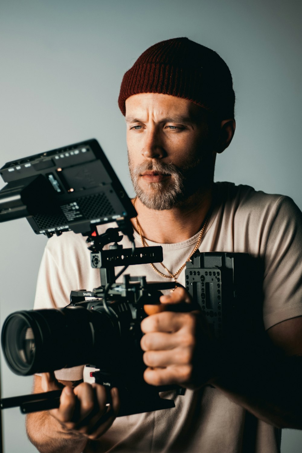 man in black knit cap holding black video camera