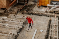 man in red jacket and black pants walking on gray concrete stairs