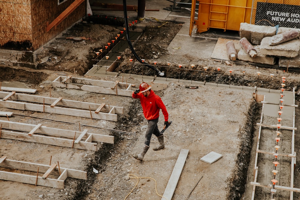 Homme en veste rouge et pantalon noir marchant sur des escaliers en béton gris