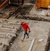 man in red jacket and black pants walking on gray concrete stairs