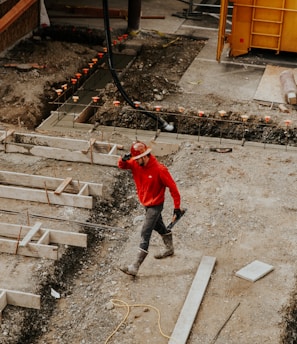 man in red jacket and black pants walking on gray concrete stairs