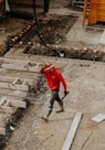 man in red jacket and black pants walking on gray concrete stairs