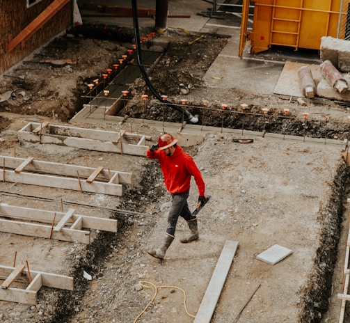 man in red jacket and black pants walking on gray concrete stairs