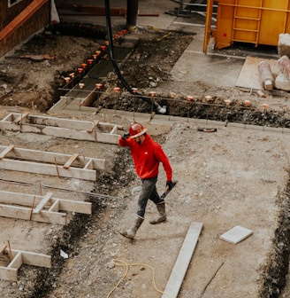 man in red jacket and black pants walking on gray concrete stairs