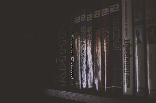A dark, atmospheric shot of the book leaning against a black wall with subtle reflections.