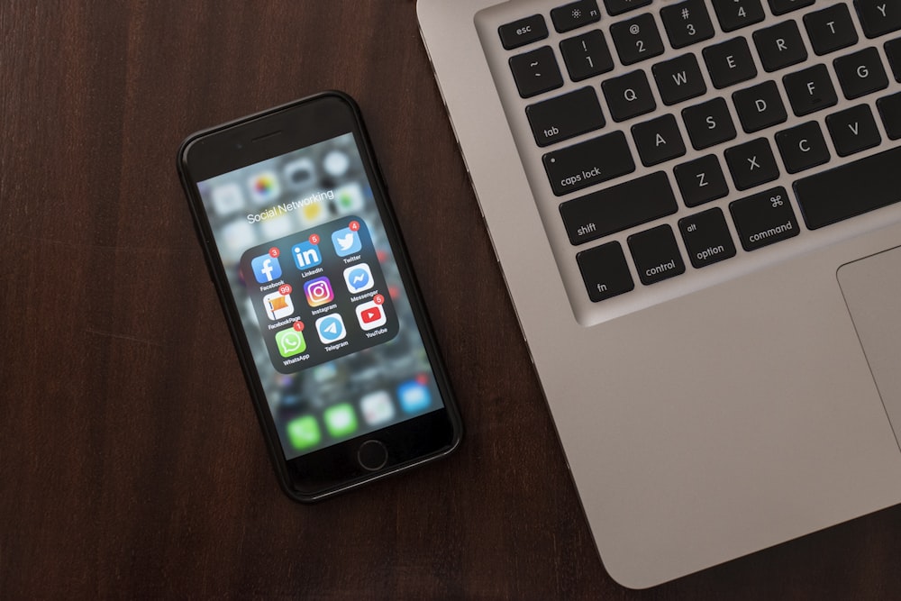 black iphone 4 beside macbook pro