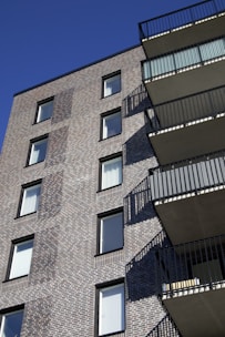 Elegant red brick apartment building with balconies and blue sky background