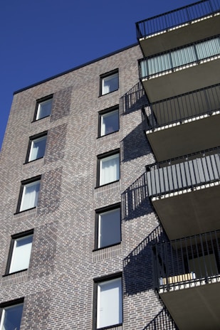 Elegant red brick apartment building with balconies and blue sky background
