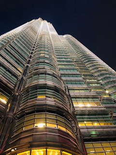 A striking nighttime shot of a towering luxury skyscraper with golden lights illuminating its sleek facade.