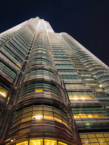 A striking nighttime shot of a towering luxury skyscraper with golden lights illuminating its sleek facade.
