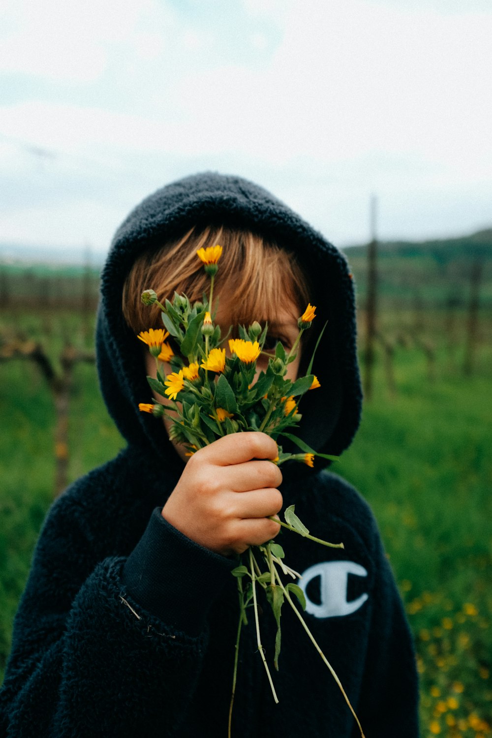 woman in black hoodie holding yellow and green flower bouquet