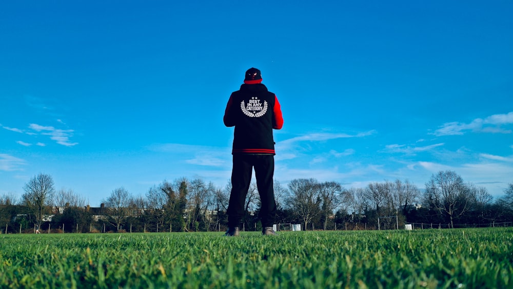 man in black hoodie standing on green grass field during daytime