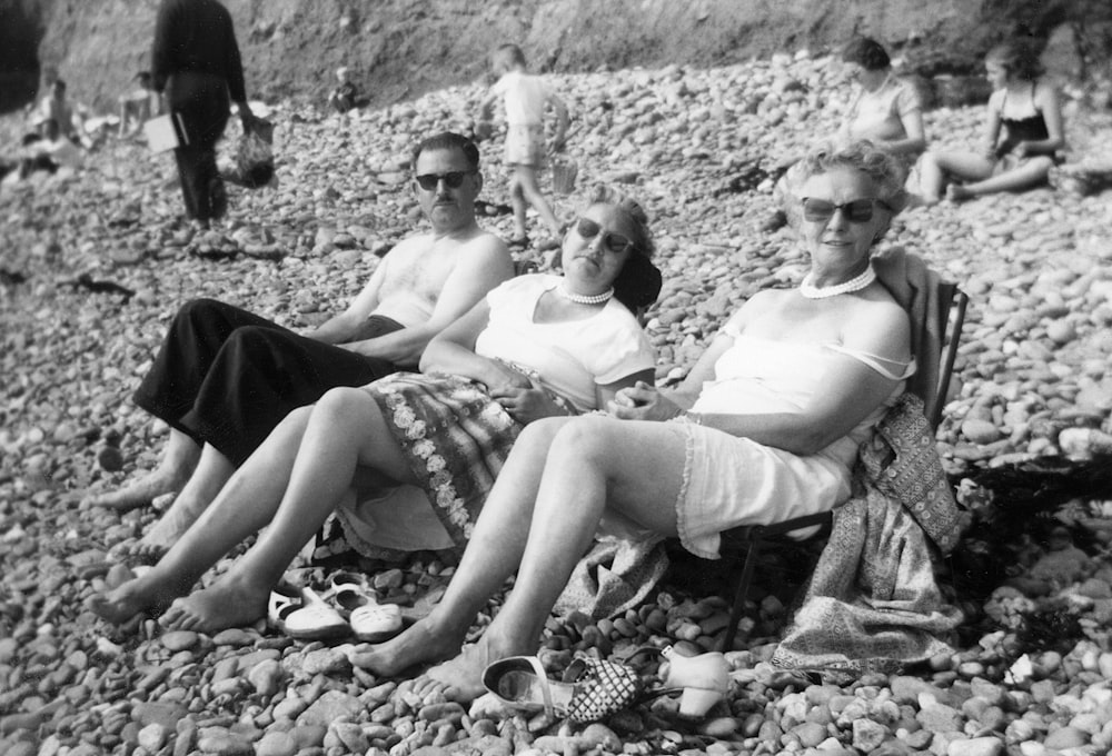 a group of women sitting on top of a rocky beach