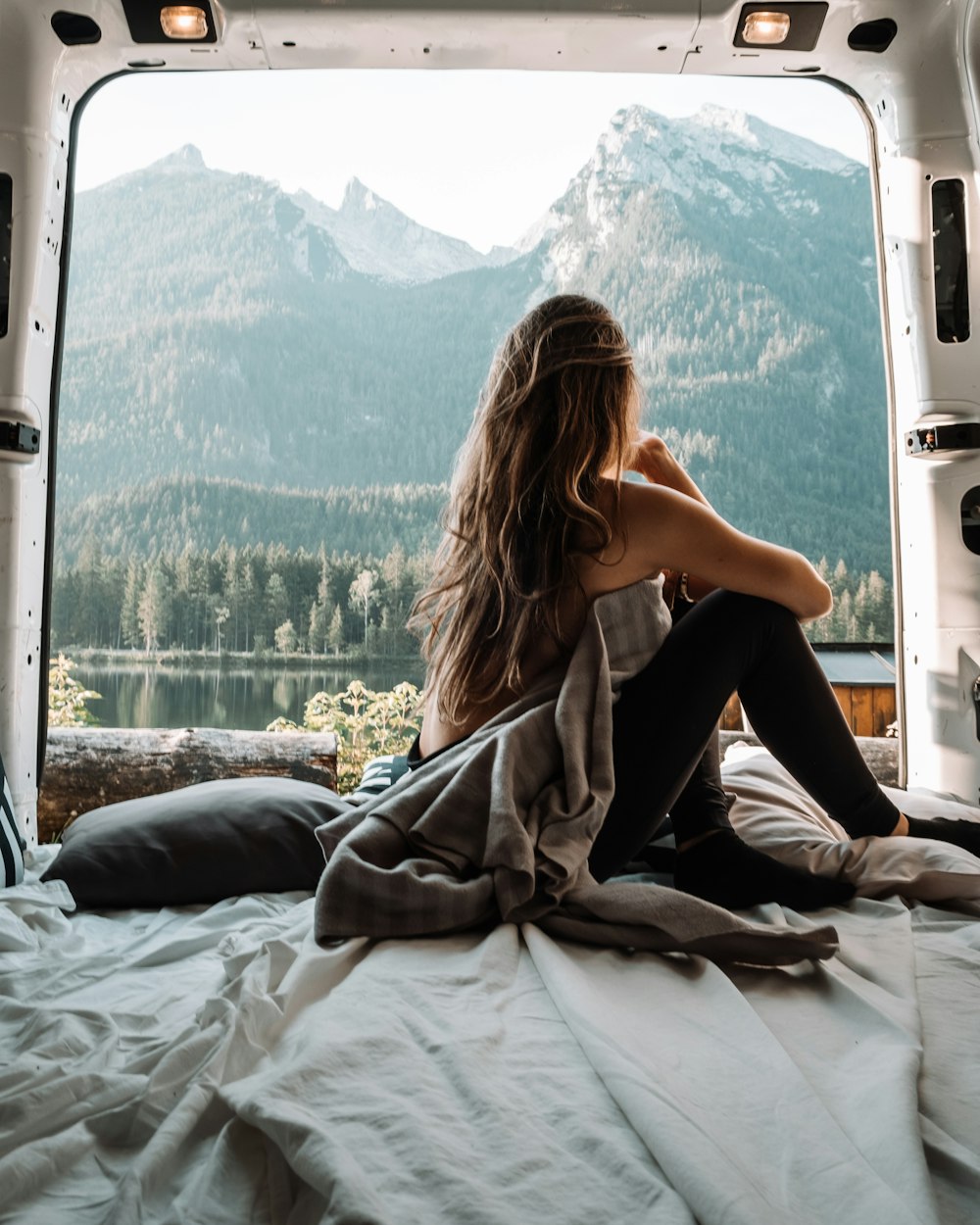 woman in black tank top and black pants sitting on bed