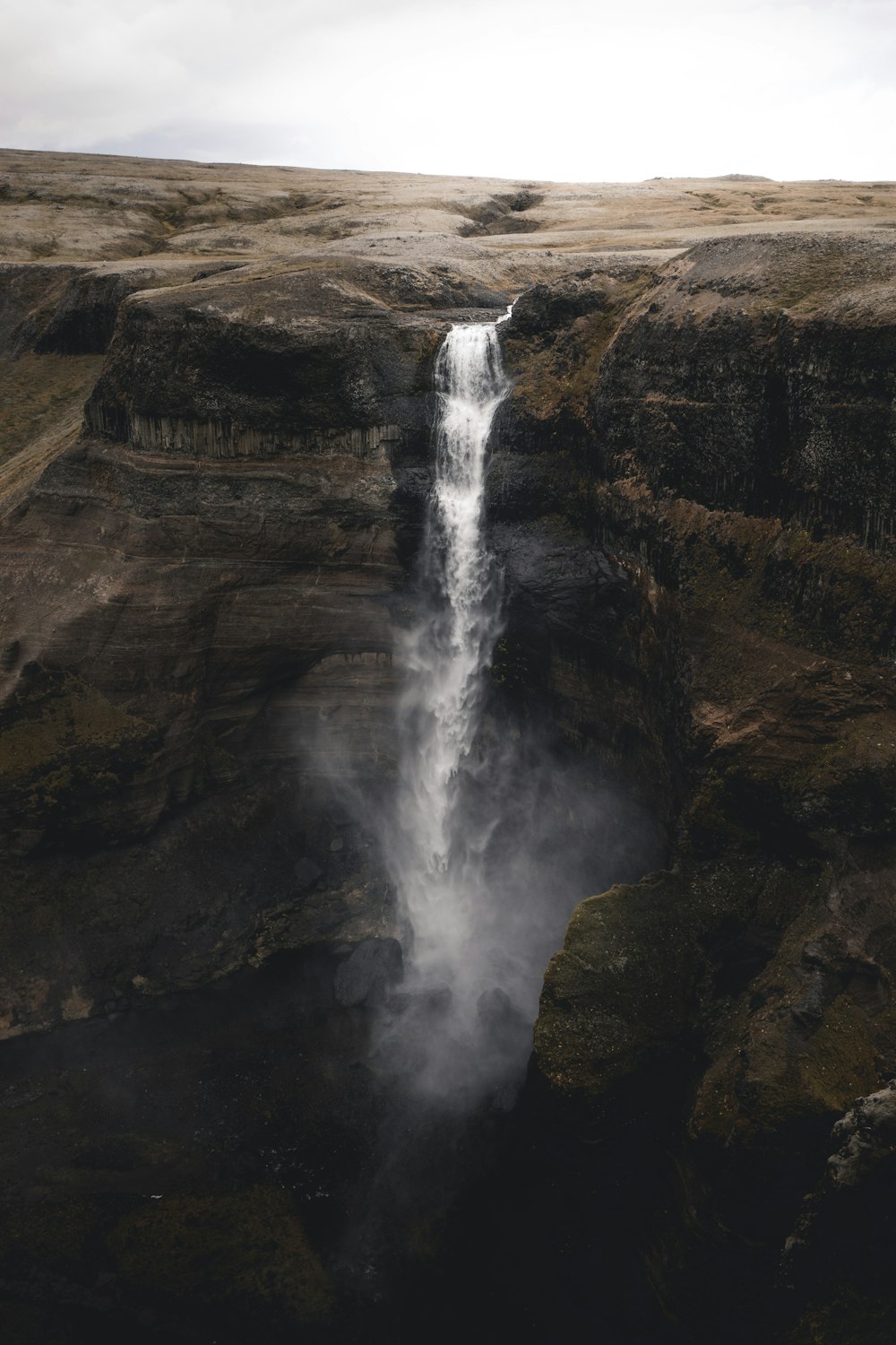 water falls on brown rocky mountain during daytime