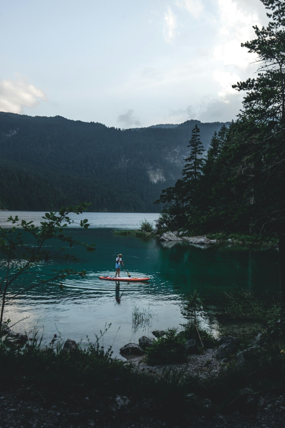 person riding on red kayak on lake during daytime