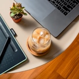 clear glass cup on white ceramic plate beside macbook pro