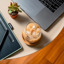 clear glass cup on white ceramic plate beside macbook pro