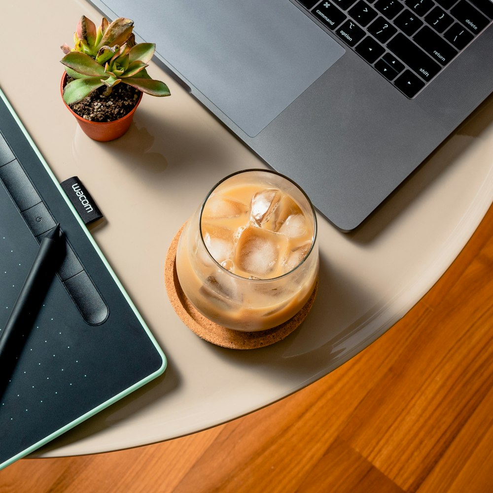 clear glass cup on white ceramic plate beside macbook pro