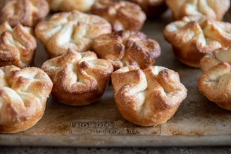 Golden brown pastry puffs are arranged closely together on a baking sheet, showcasing a flaky, crisp texture.