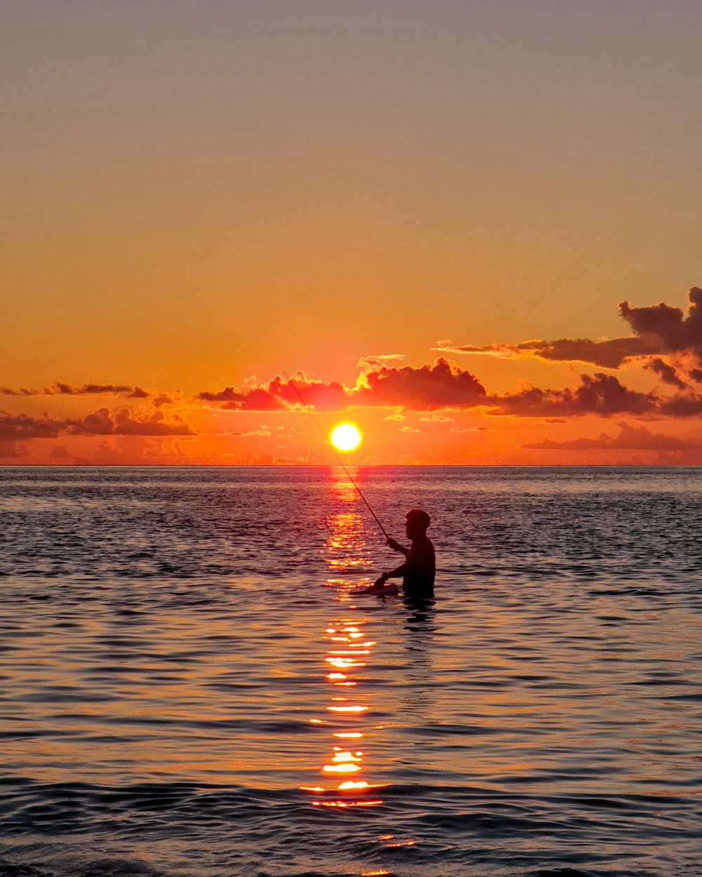 Silueta del hombre y de la mujer en el cuerpo de agua durante la puesta del sol