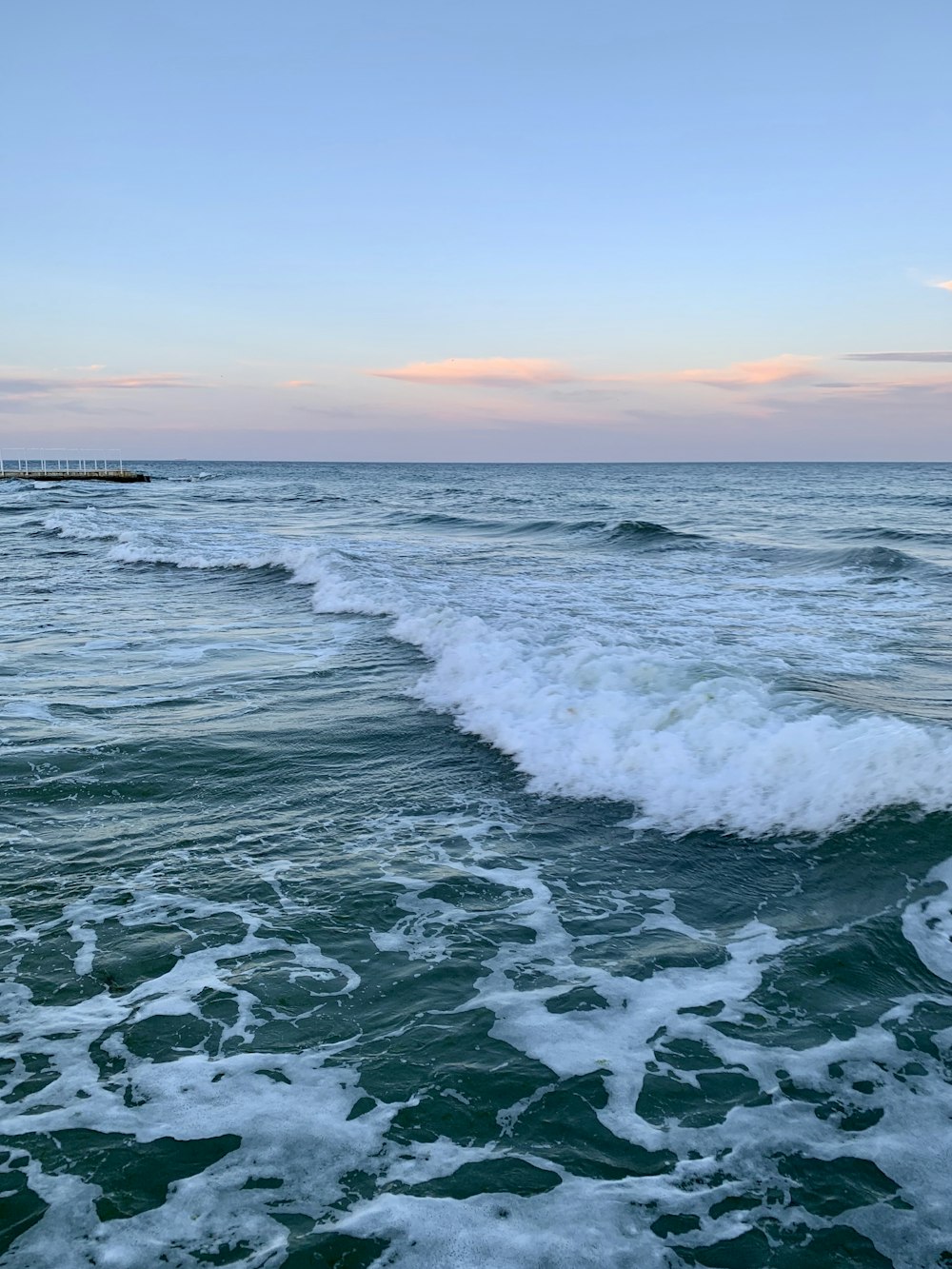 ocean waves crashing on shore during sunset