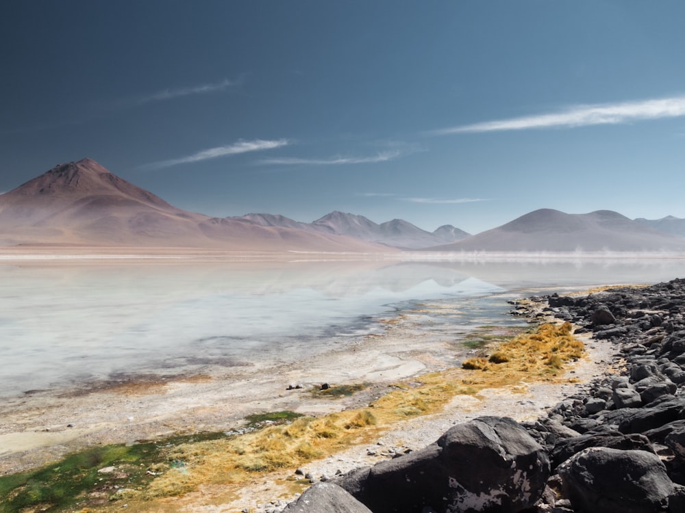 body of water near mountain under blue sky during daytime