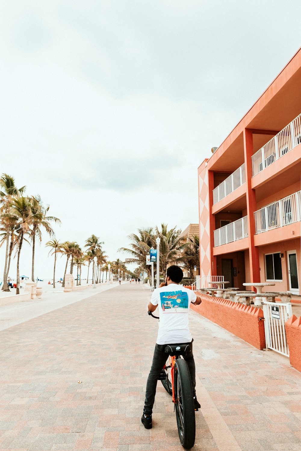 man in white t-shirt and black pants walking on sidewalk during daytime