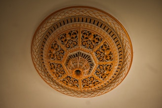 An intricately designed architectural dome with ornate floral patterns and geometric motifs in shades of gold and brown. The craftsmanship exhibits elaborate detailing, contributing to a sense of luxury and elegance.