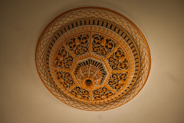 An intricately designed architectural dome with ornate floral patterns and geometric motifs in shades of gold and brown. The craftsmanship exhibits elaborate detailing, contributing to a sense of luxury and elegance.