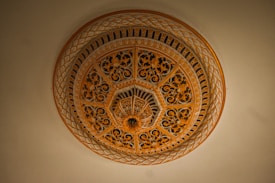 An intricately designed architectural dome with ornate floral patterns and geometric motifs in shades of gold and brown. The craftsmanship exhibits elaborate detailing, contributing to a sense of luxury and elegance.